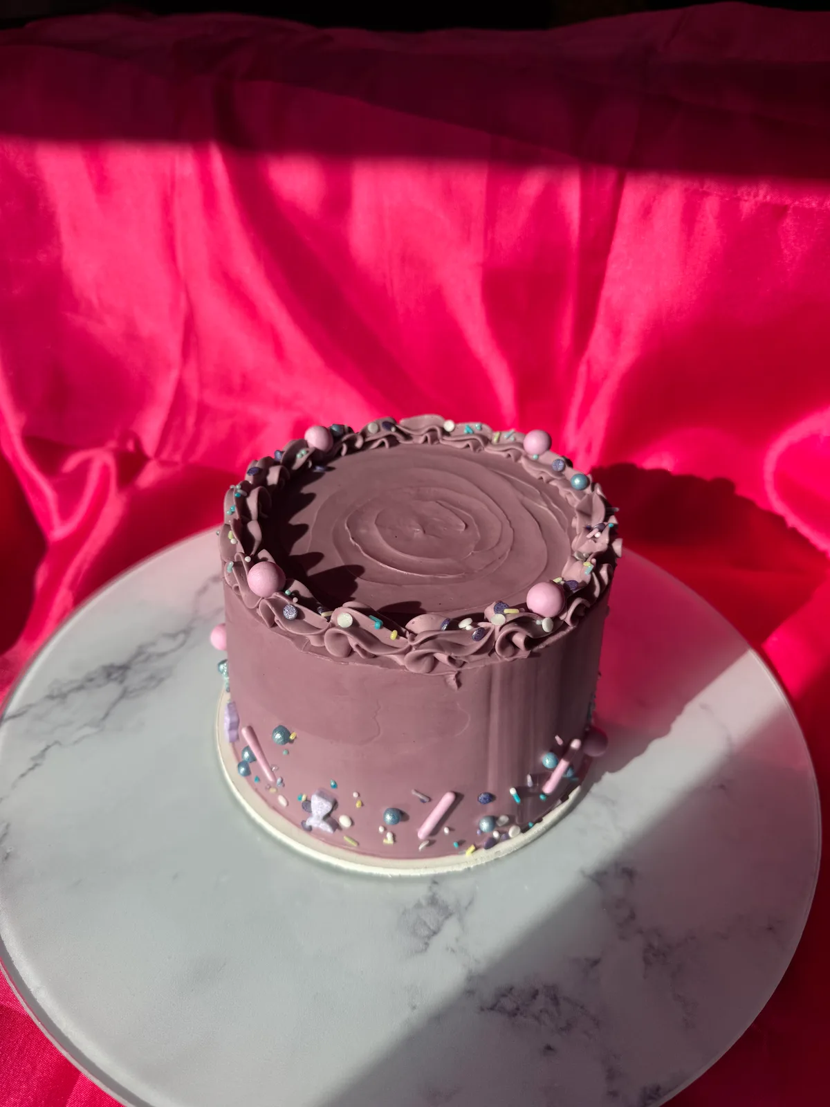 Bolo de brigadeiro lilás com borda de babados de buttercream, pérolas e confeitos
