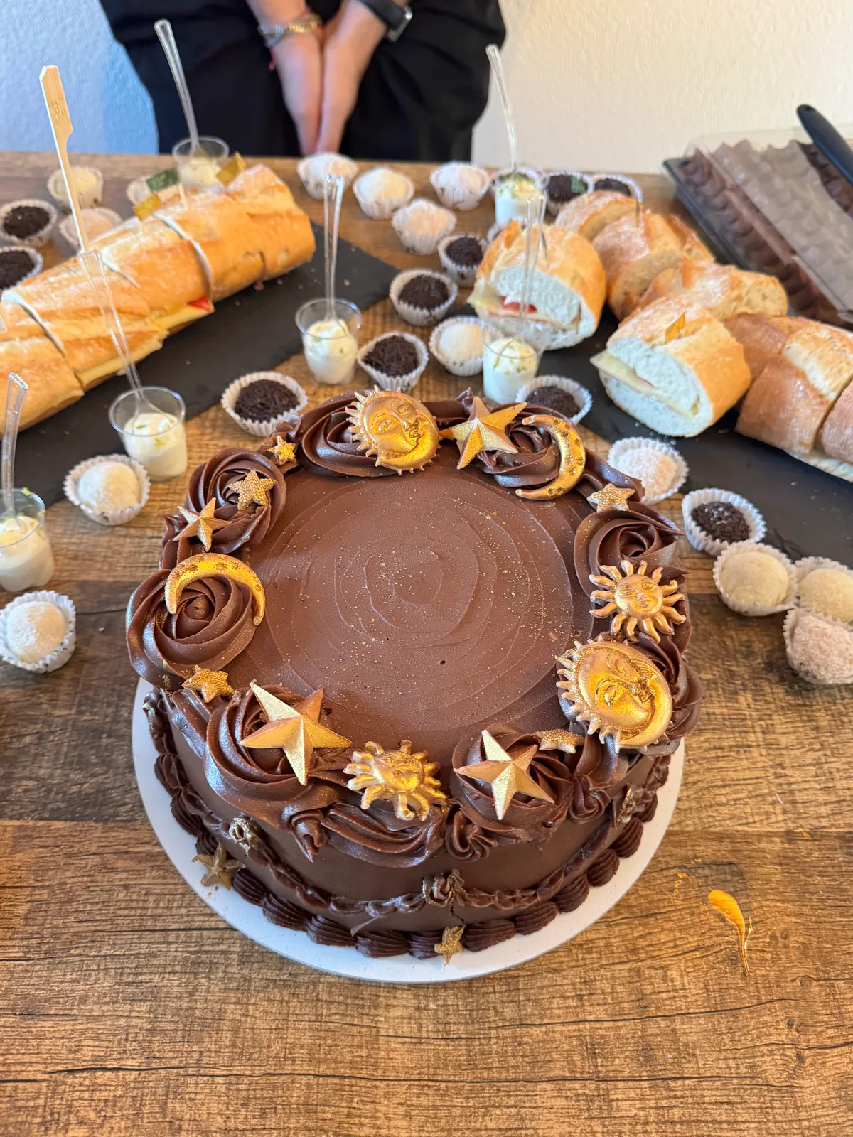 Bolo de chocolate com decoração dourada de sol, lua e estrelas